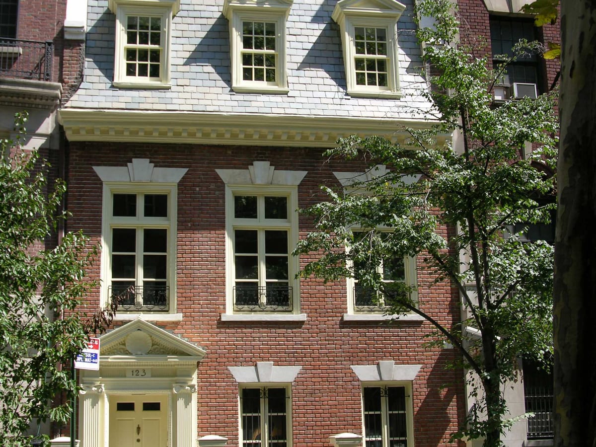 A brick NYC townhome with painted wood double-hung windows and dormers