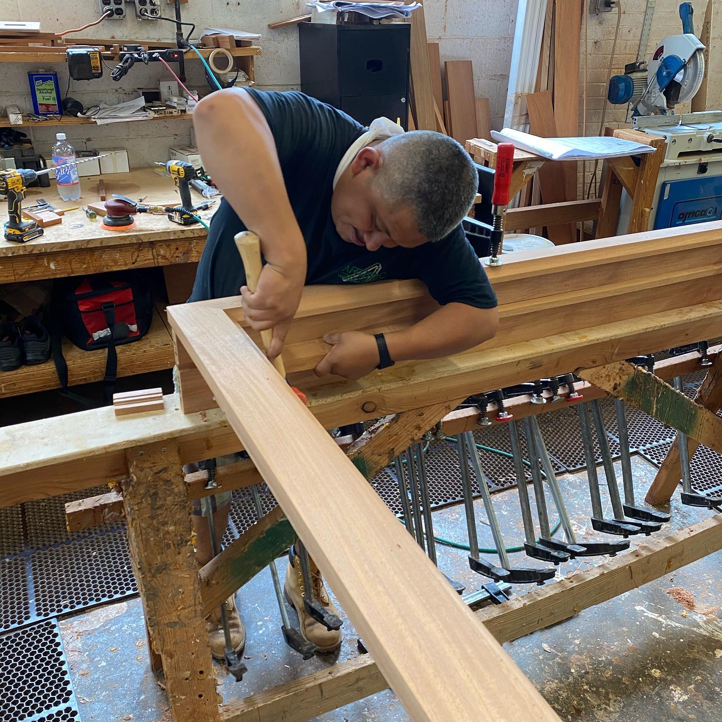 An Artistic craftsman hand-fitting a wood beam on the workbench, clamped and ready for shaping